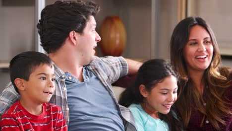 Familie-sitzt-auf-dem-Sofa-vor-dem-Fernseher-und-Essen-Popcorn