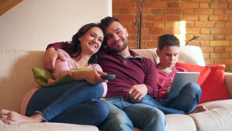 Eltern,-die-vor-dem-Fernseher-während-Sohn-mit-digital-Tablette-zu-Hause