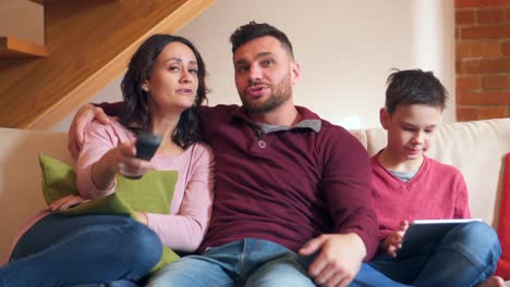 Junge-mit-digital-Tablette-während-seiner-Eltern-vor-dem-Fernseher