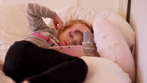 A-little-girl-laying-on-her-bedroom-floor-watching-a-show-on-her-handheld-gaming-system