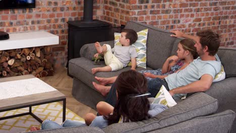 Familie-sitzen-auf-Sofa-in-Open-Plan-Lounge-Fernsehen