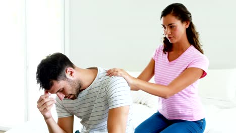 Woman-comforting-man-sitting-on-bed