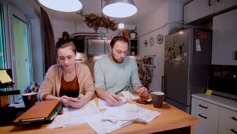 Pareja-joven-triste-pagar-las-facturas.-Hombre-y-la-mujer-sentada-en-la-cocina-y-clasificación-de-cheques-y-cuentas-de