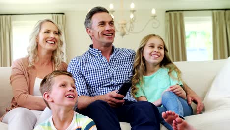 Glückliche-Familie-vor-dem-Fernseher-im-Wohnzimmer