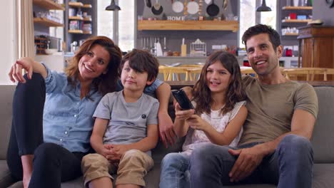 Familie-auf-Sofa-In-offenes-Wohnzimmer-vor-dem-Fernseher-sitzen