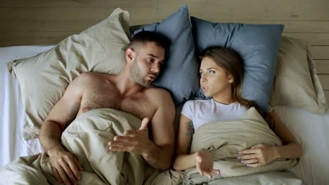 Top-view-of-young-couple-lying-in-bed-upset-and-argue-each-other
