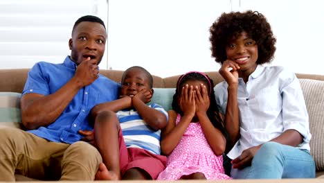 Family-sitting-on-sofa-and-watching-television