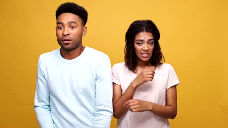 Frustrado-afro-americano-joven-tener-un-desacuerdo-con-su-novia-culpable-aislada-sobre-fondo-amarillo