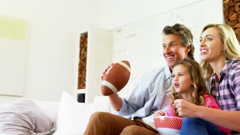 Lächelnde-Familie-vor-dem-Fernseher-während-mit-Popcorn-im-Wohnzimmer-4k