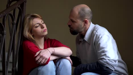 angry-woman-sitting-on-the-stairs-is-reached-by-the-boyfriend-comforting-her