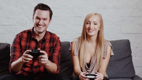 young-man-and-woman-are-sitting-on-the-couch-and-are-playing-a-game