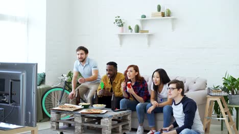 Gruppe-der-happy-Friends-Sportspiel-im-Fernsehen-zu-Hause-beobachten.-Sie-springen-und-schreien,-während-Sie-ihre-Lieblings-Team-gewinnen-Wettbewerb