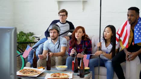 Diverse-group-of-friends-sports-fans-with-USA-national-flags-watching-hockey-championship-on-TV-together-cheering-up-their-favourite-team-at-home