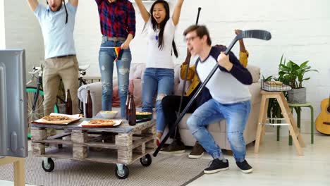 Group-of-young-friends-sports-fans-with-German-national-flags-watching-sport-championship-on-TV-together-and-happy-about-winning-favourite-team-at-home