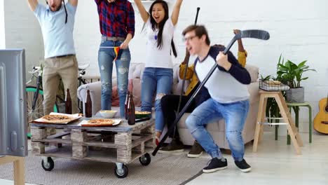 Multi-ethnic-group-of-friends-sports-fans-with-German-national-flags-watching-hockey-championship-on-TV-together-cheering-up-their-favourite-team-at-home