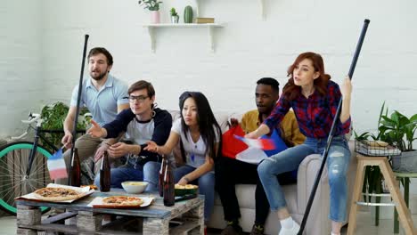 Grupo-de-jóvenes-amigos-deportes-aficionados-con-banderas-nacionales-francesas-ver-Campeonato-del-deporte-en-la-televisión-juntos-animando-hasta-equipo-favorito-en-casa