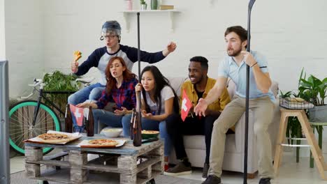 Group-of-young-friends-sports-fans-with-Swiss-national-flags-watching-sport-championship-on-TV-together-and-happy-about-winning-favourite-team-at-home