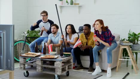 Grupo-de-jóvenes-amigos-de-deportes-aficionados-con-banderas-nacionales-austríacos-mirando-Campeonato-del-deporte-en-la-televisión-junto-y-feliz-por-ganar-el-equipo-favorito-en-casa