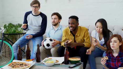 Multi-ethnische-Gruppe-von-Freunden-Sport-Fans,-die-Fußball-EM-im-Fernsehen-zusammen-Pizza-essen-und-Bier-zu-Hause-beobachten