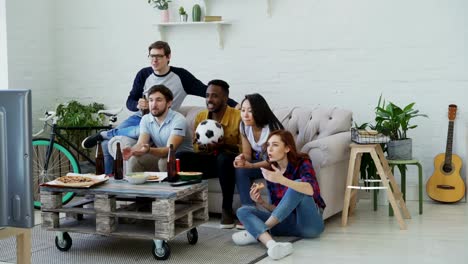 Amigos-felizes-ver-Campeonato-de-deportes-en-la-televisión-juntos-en-casa-mientras-comer-bocadillos-y-bebiendo-cerveza-en-el-país.-Son-felices-de-ganar-del-equipo-favorito