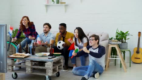 Happy-friends-with-French-flags-watching-sports-championship-on-TV-together-at-home-and-happy-about-winning-of-favourite-team