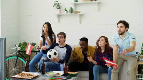 Multi-ethnischen-Gruppe-von-Freunden-Sport-Fans-mit-österreichischen-Fahnen-gerade-Fußball-EM-im-Fernsehen-zu-Hause-zusammen-und-Aufmunterung-Lieblingsmannschaft