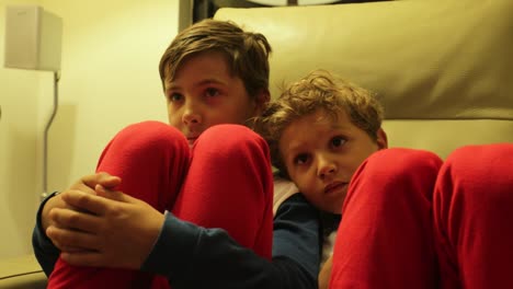 Die-jungen-sitzen-auf-dem-Sofa-vor-dem-Fernseher-hinter-der-Kamera.-4K-candid-Clip-von-Kindern,-die-auf-Bildschirm-zu-Hause