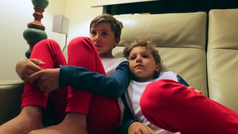 Die-jungen-sitzen-auf-dem-Sofa-vor-dem-Fernseher-hinter-der-Kamera.-4K-candid-Clip-von-Kindern,-die-auf-Bildschirm-zu-Hause