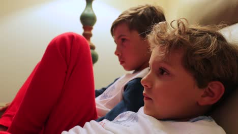 Die-jungen-sitzen-auf-dem-Sofa-vor-dem-Fernseher-hinter-der-Kamera.-4K-candid-Clip-von-Kindern,-die-auf-Bildschirm-zu-Hause