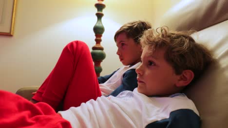 Die-jungen-sitzen-auf-dem-Sofa-vor-dem-Fernseher-hinter-der-Kamera.-4K-candid-Clip-von-Kindern,-die-auf-Bildschirm-zu-Hause