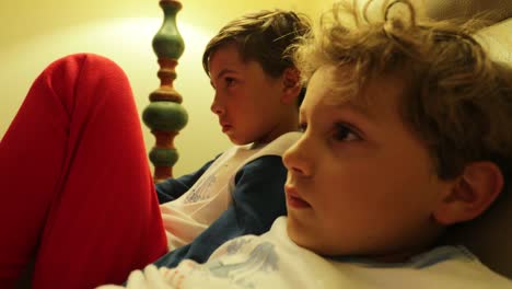 Die-jungen-sitzen-auf-dem-Sofa-vor-dem-Fernseher-hinter-der-Kamera.-4K-candid-Clip-von-Kindern,-die-auf-Bildschirm-zu-Hause