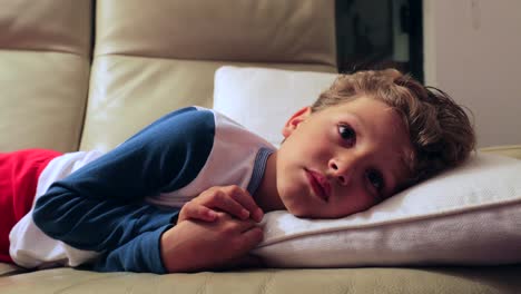 Candid-4K-clip-of-young-boy-starring-at-TV-screen-at-night.-Child-layed-in-sofa-watching-screen