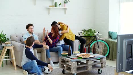 Football-fans-watching-match-on-TV-and-enjoying-victory-of-favourite-team-while-sitting-on-couch-at-home