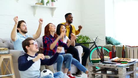 Amigos-felices-del-deporte-fans-viendo-el-juego-de-deportes-en-la-televisión-en-casa.-Que-animar-para-arriba-equipo-favorito-y-aplaudiendo-las-manos