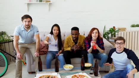 Slow-motion-of-group-of-happy-friends-watching-sports-game-on-TV-at-home.-They-are-yelling-while-their-favorite-team-win-competition