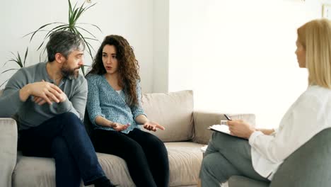 Mujer-enojada-discutiendo-y-hablando-de-su-marido-consejero-de-matrimonio.-Pareja-joven-visita-oficina-de-profesional-psicólogo