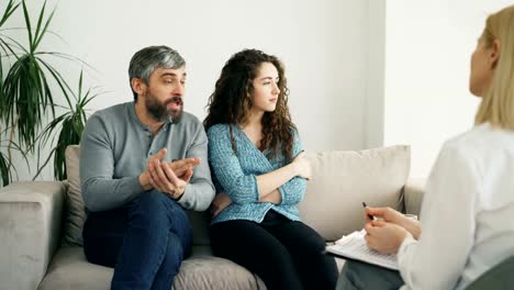 Verärgerter-Mann-streiten-und-reden-über-seine-Frau,-Eheberater.-Junges-Paar-Besuch-professionellen-Psychologen-Büro