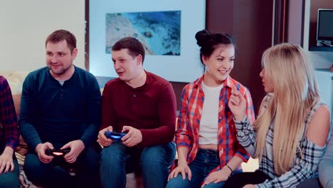 Company-of-the-friends-enjoy-relaxing-on-couch-playing-videogames-and-having-fun-in-modern-flat