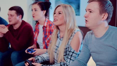 Happy-group-of-laughing-male-and-female-friends-playing-video-games-with-wireless-controllers