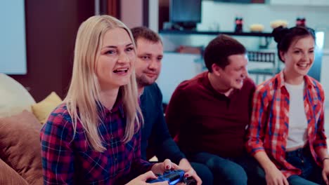 Company-of-the-friends-enjoy-relaxing-on-couch-playing-videogames-and-having-fun-in-modern-flat