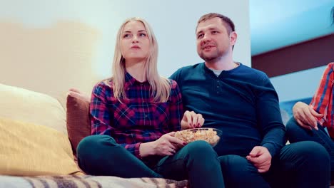 Freunden-auf-der-Couch-sitzen,-Fernsehen,-reden,-lachen-und-Essen-popcorn