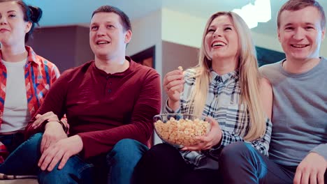 Company-of-friends-watching-a-comedy-on-TV,-laughing-and-eating-popcorn