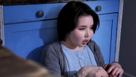 Traurig-einsam-junge-asiatische-Mädchen-sitzen-auf-dem-Boden-in-Küche,-halten-Sie-ihre-Knie-mit-Armen,-häusliche-Gewalt-Konzept-50-fps