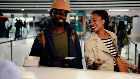 Young-couple-taking-boarding-passes-at-airport-check-in-desk