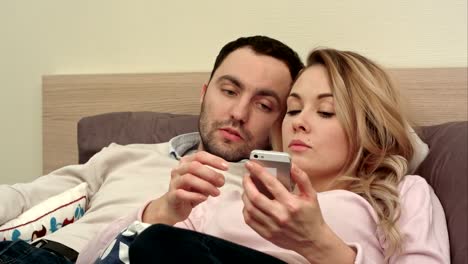 Young-couple-fighting,-arguing-in-bed-at-night-because-woman-texting-someone-using-smartphone
