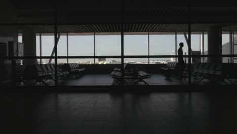 Silhouette-of-Man-Walking-in-Airport-Waiting-Area