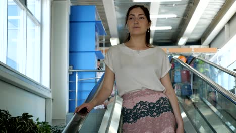 young-woman-rides-on-an-escalator,-holding-onto-a-railing