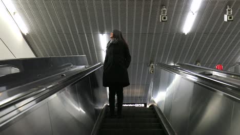 Woman-descending-on-modern-electric-escalator-stairs.-Girl-going-down-a-floor-standing-still-in-4K