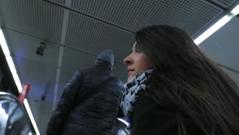 Woman-going-up-on-a-moving-electric-escalator.-Candid-4K-of-travel-girl-in-urban-underground-setting.-Modern-escalator-stairs-moving-up