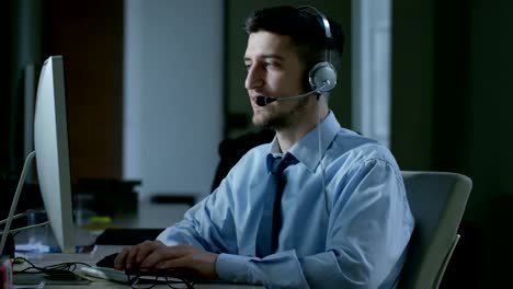 Un-hombre-joven,-que-trabaja-en-servicio-al-cliente-o-en-alguna-estación-de-torre-de-control-del-aeropuerto,-responde-a-las-llamadas-a-los-clientes-de-teléfono-con-una-sonrisa-día-y-noche.